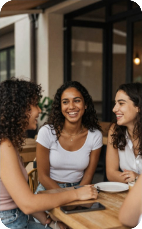 Three friends laughing together over dinner